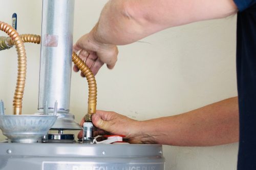Adult male making adjustments and tightening connections on new hot water heater