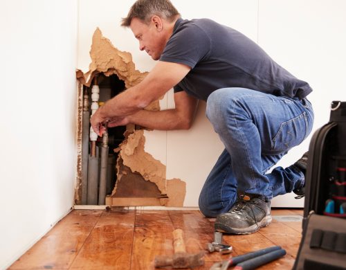 Middle aged man repairing burst water pipe